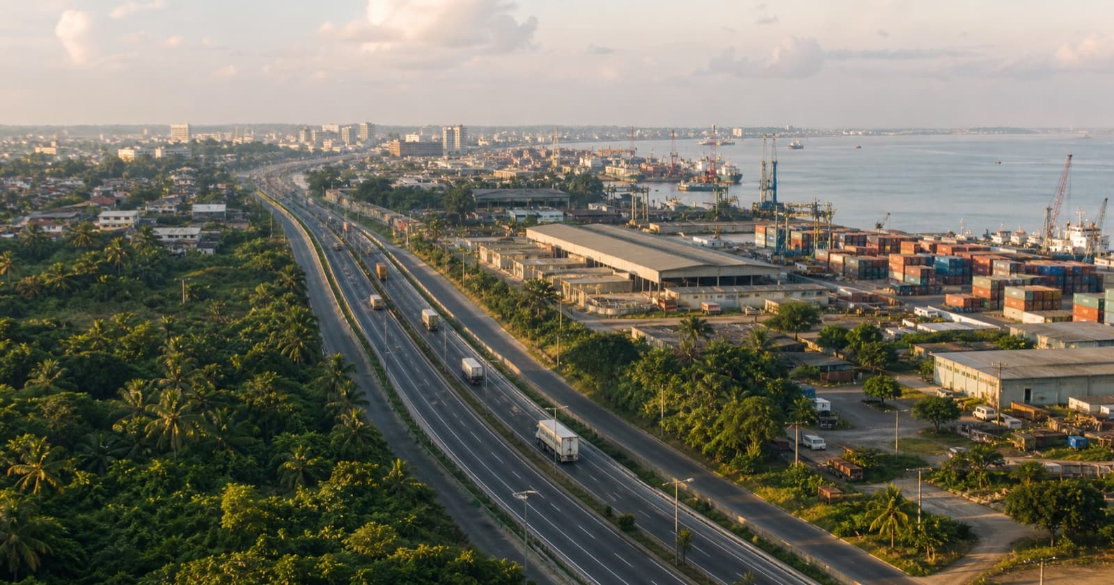 Coastal West African highway connecting a logistics district, warehouses, port, and growing city